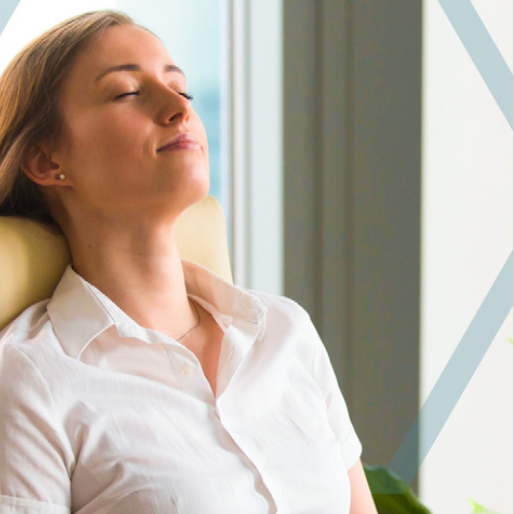 Woman at an office with eyes closed relaxing.
