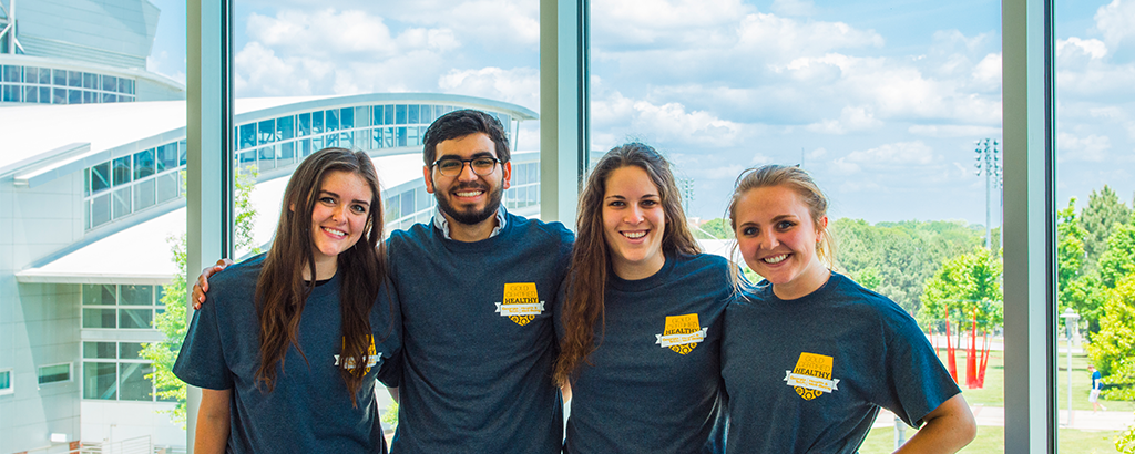 Three GT women and one man students wearing VOICE Peer Educators T-Shirts