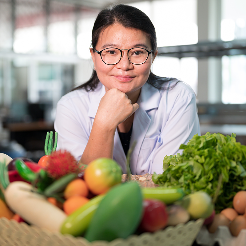A woman nutritionist behind a basket full of veggies.